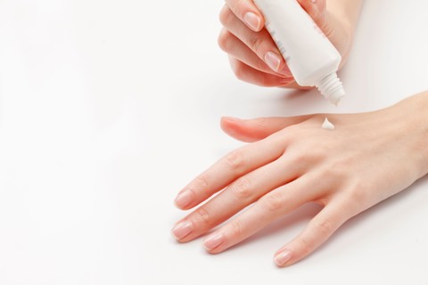 Close up of woman's hands applying moisturizer, studio shot. Photo : Jan Scherders