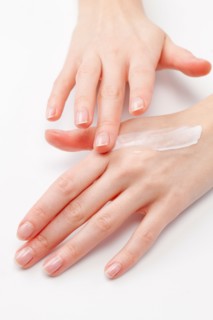 Close up of woman's hands applying moisturizer, studio shot. Photo : Jan Scherders