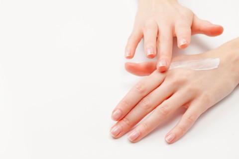 Close up of woman's hands applying moisturizer, studio shot. Photo : Jan Scherders