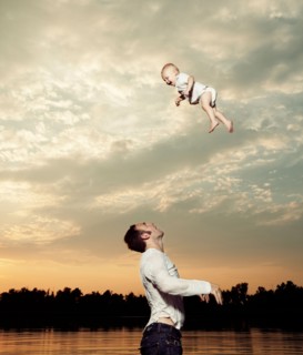 Father tossing baby son up in air. Photo : King Lawrence