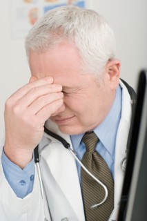 Doctor rubbing forehead. Photo : Rob Lewine