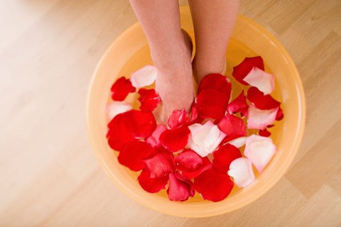 Woman soaking feet in water with rose petals. Photo : Rob Lewine