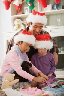 Father and daughters (10-11) unwrapping christmas gifts. Photo : Rob Lewine