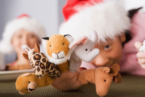 Girl wearing Santa hat playing with finger puppets. Photo : Rob Lewine