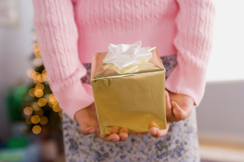 Close-up of girl holding Christmas present behind back, mid section. Photo : Rob Lewine