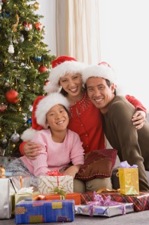 Portrait of parents with daughter (10-11) at Christmas tree. Photo : Rob Lewine