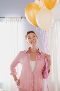 Smiling mature woman holding balloons. Photo : Rob Lewine
