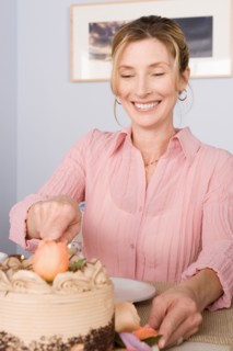 Portrait of mature woman cutting cake. Photo : Rob Lewine