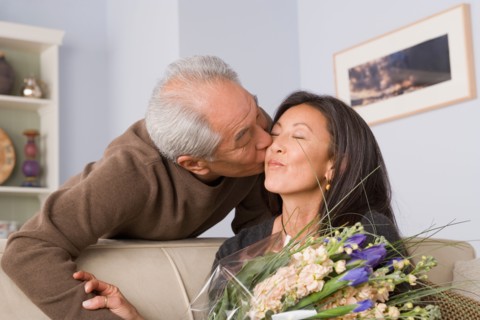 Woman receiving kiss and flowers from husband. Photo : Rob Lewine