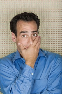 Studio portrait of mid adult man covering mouth with hand. Photo : Rob Lewine