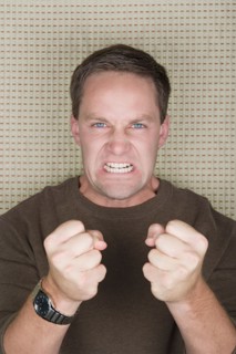 Studio portrait of mature man clenching teeth and fists. Photo : Rob Lewine