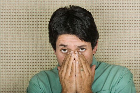 Studio portrait of mature man covering mouth with hands. Photo : Rob Lewine