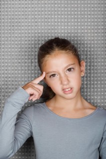 Studio portrait of teenage (12-13) girl touching forehead with finger. Photo : Rob Lewine