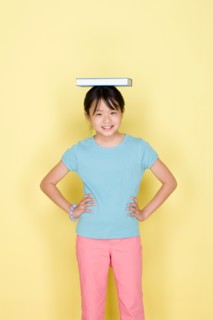 Studio portrait of teenage (16-17) girl balancing book on head. Photo : Rob Lewine
