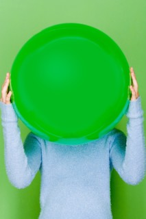 Studio shot portrait of teenage girl holding ball in front of her face, waist up. Photo : Rob