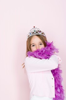 Studio shot portrait of teenage girl in diadem and feather boa shawl, waist up. Photo : Rob Lewine