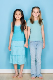 Studio shot portrait of two teenage girls holding hands, full length. Photo : Rob Lewine
