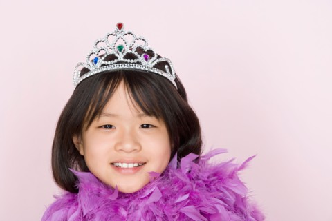 Studio shot portrait of teenage girl in diadem and feather boa shawl, head and shoulders. Photo :