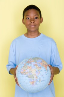 Studio shot portrait of young man holding globe ball, waist up. Photo : Rob Lewine