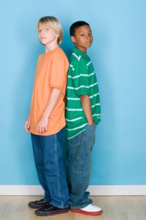 Studio shot portrait of two teenagers standing back to back, full length. Photo : Rob Lewine