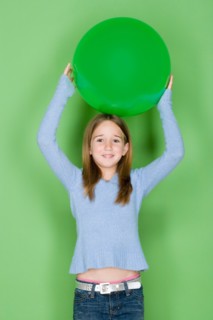Studio shot portrait of teenage girl holding ball on her head, waist up. Photo : Rob Lewine