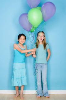 Studio shot portrait of two teenage girls holding balloons, full length. Photo : Rob Lewine