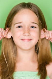 Studio shot portrait of teenage girl pulling her ears, close-up. Photo : Rob Lewine