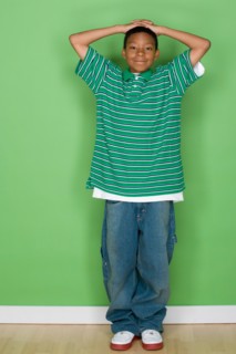 Studio shot portrait of young man with hands behind head, full length. Photo : Rob Lewine