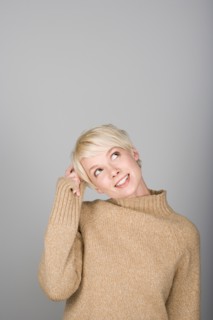 Studio shot portrait of young woman scratching head, waist up. Photo : Rob Lewine