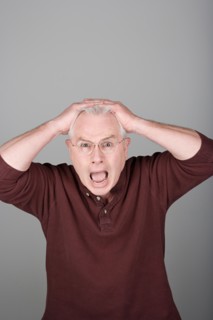 Studio shot portrait of senior man with head in hands and open mouth, waist up. Photo : Rob Lewine