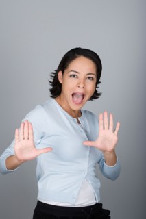 Studio shot portrait of mid adult woman with arms raised and open mouth, waist up. Photo : Rob