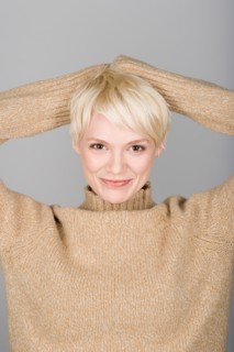 Studio shot portrait of mid adult woman with hands behind head, head and shoulders. Photo : Rob