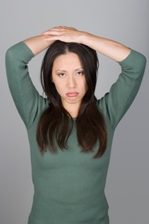 Studio shot portrait of mid adult woman with arms raised, waist up. Photo : Rob Lewine