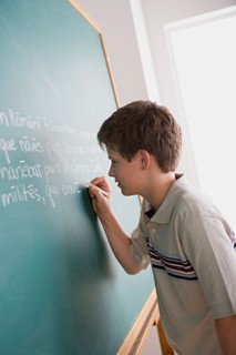 Boy writing on blackboard. Photo : Rob Lewine