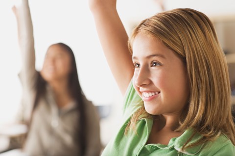 Schoolgirl rising hand in classroom. Photo : Rob Lewine