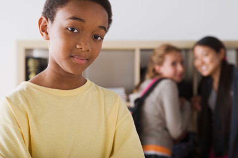 Portrait of schoolboy with two gild gossiping in background. Photo : Rob Lewine