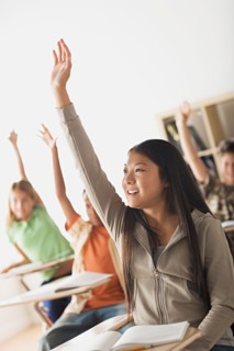 Schoolchildren rising hands in classroom. Photo : Rob Lewine