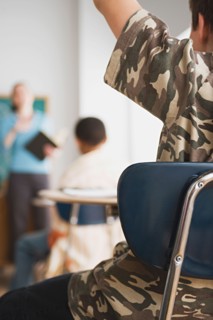rear view of schoolboy rising hand in classroom. Photo : Rob Lewine