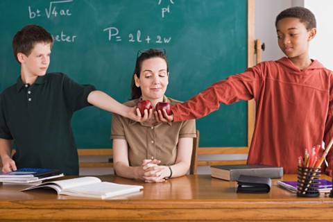 Two boys holding apples in front of teacher. Photo : Rob Lewine