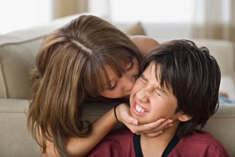 Sister kissing younger brother. Photo : Rob Lewine