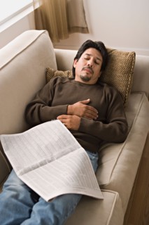 Mature man sleeping on sofa with newspaper. Photo : Rob Lewine