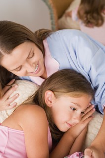 Mother lying in bed with daughter (12-13) . Photo : Rob Lewine