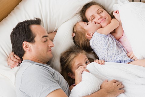 Family with two children chilling in bed. Photo : Rob Lewine