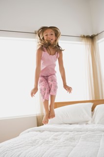 Girl jumping on bed. Photo : Rob Lewine