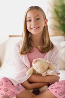 Smiling girl (12-13) holding teddy bear. Photo : Rob Lewine