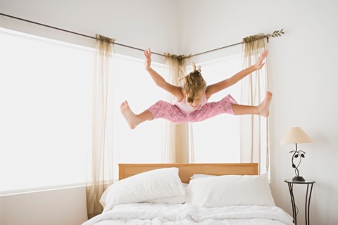Girl (12-13) jumping on bed. Photo : Rob Lewine
