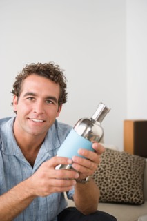 Portrait of smiling man holding cocktail shaker. Photo : Rob Lewine