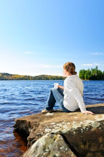 Canada, Ontario, Algonquin Park, Teenage girl sitting on rock and looking at lake. Photo :  Elena