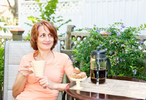 Woman having coffee in garden. Photo : Elena Elisseeva