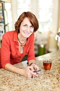 Woman in kitchen with glass of tea and cell phone. Photo : Elena Elisseeva